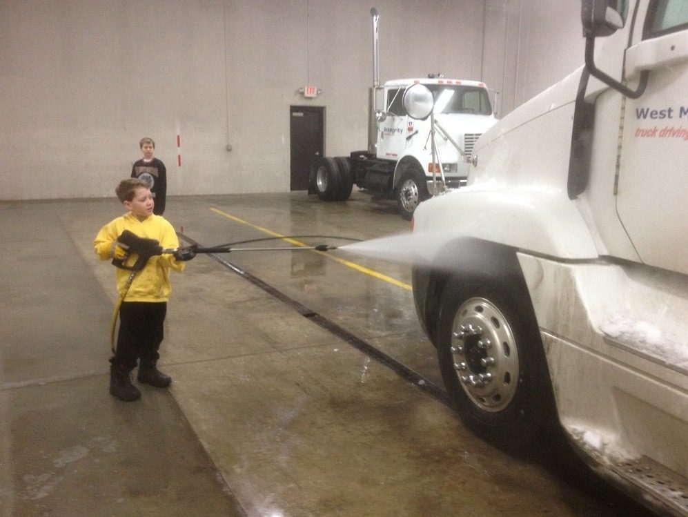 Justin as a young kid pressure-washing a semi truck