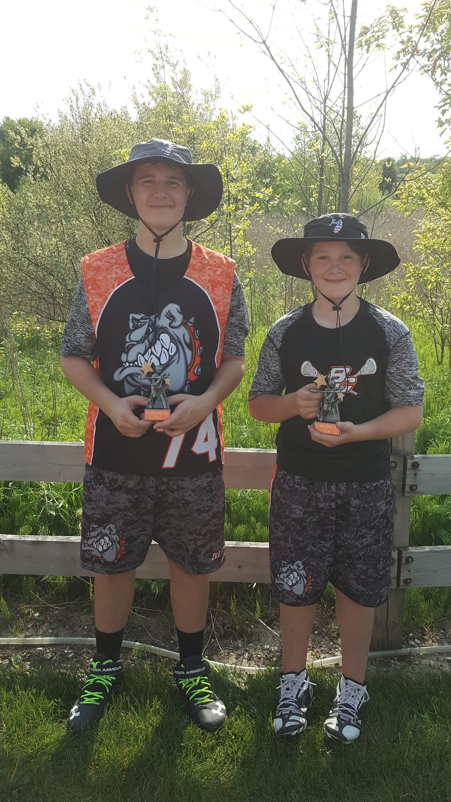 Justin and his brother in Byron Center lacrosse gear holding trophies